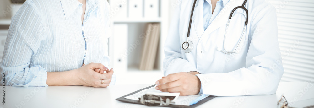 Unknown woman-doctor and patient sitting at the table. Very good news and high level medical service concept Unknown woman-doctor and patient sitting at the table. Very good news and high level medical service concept