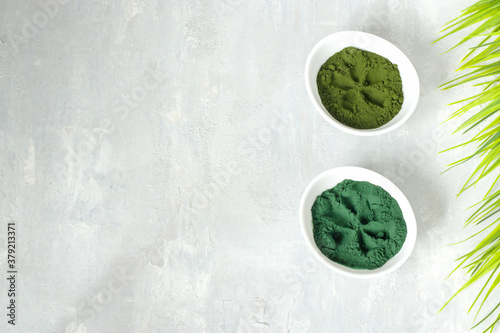 Chlorella and spirulina powder on a light background. A green superfood detox for a vegetarian diet. Healthy lifestyle concept. Copy space