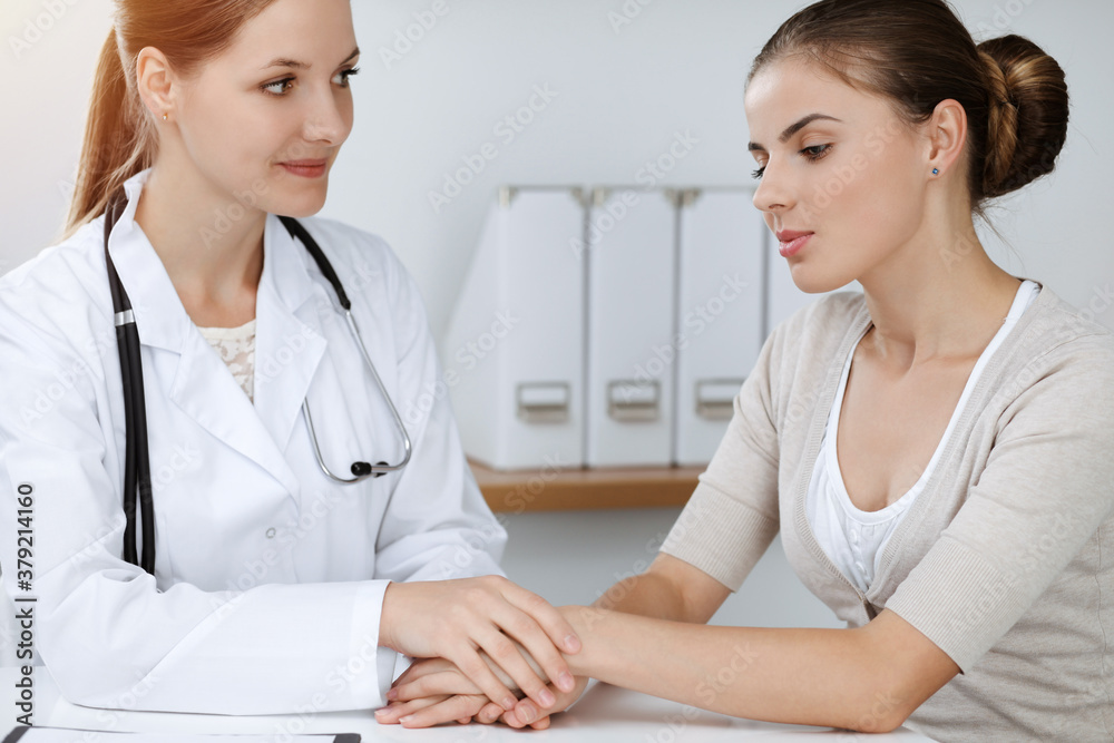 Doctor and patient sitting and discussing health examination results in sunny clinic Doctor and patient sitting and discussing health examination results in sunny clinic