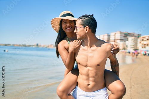 Young latin couple wearing swimwear smiling happy walking at the beach.