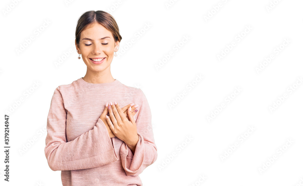 Beautiful caucasian woman with blonde hair wearing casual winter sweater smiling with hands on chest with closed eyes and grateful gesture on face. health concept.