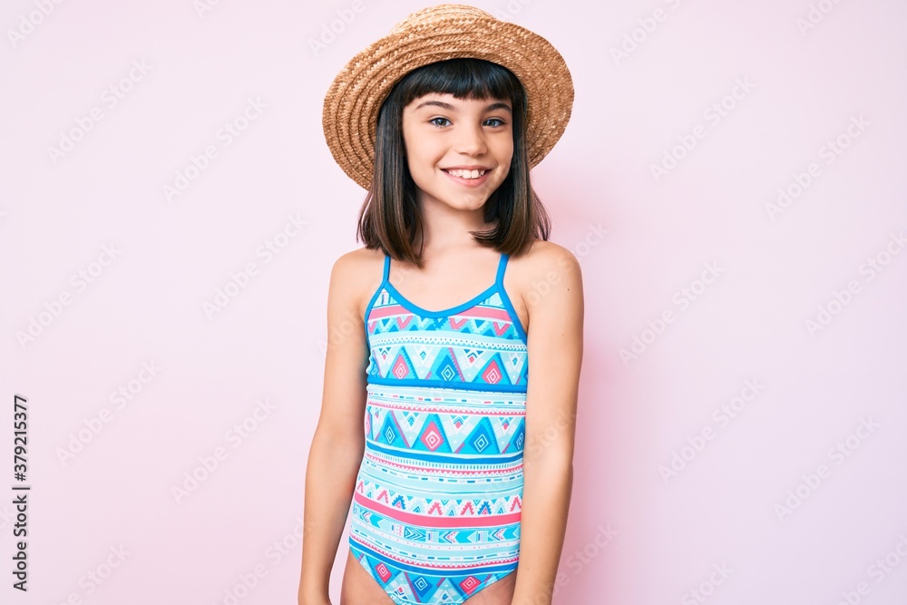 Young little girl with bang wearing swimsuit and summer hat with a happy and cool smile on face. lucky person. Young little girl with bang wearing swimsuit and summer hat with a happy and cool smile on face. lucky person.