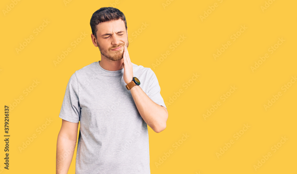 Handsome young man with bear wearing casual tshirt touching mouth with hand with painful expression because of toothache or dental illness on teeth. dentist