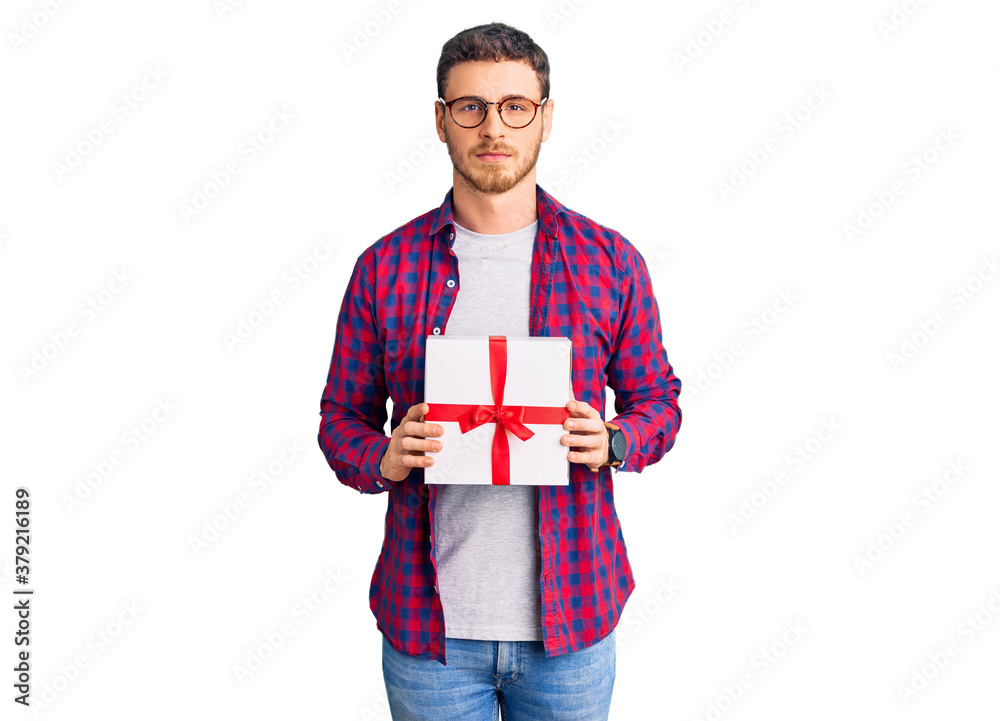 Handsome young man with bear holding gift thinking attitude and sober expression looking self confident Handsome young man with bear holding gift thinking attitude and sober expression looking self confident