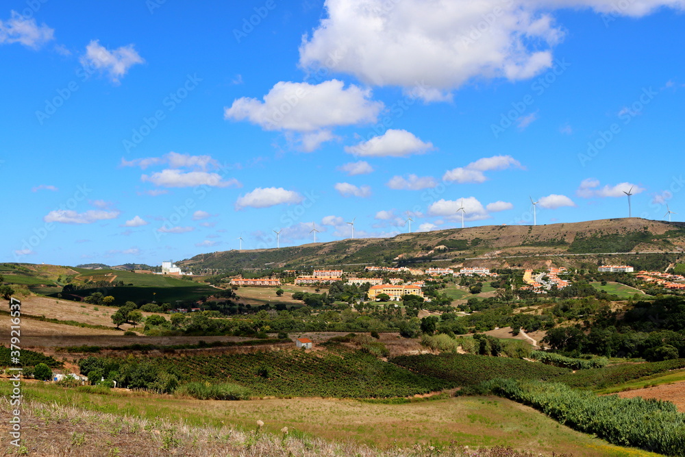 Wonderful panoramic views of the natural landscapes of Portugal. View of blue skies, high hills, wind turbines and traditional ceramic tiled roof houses