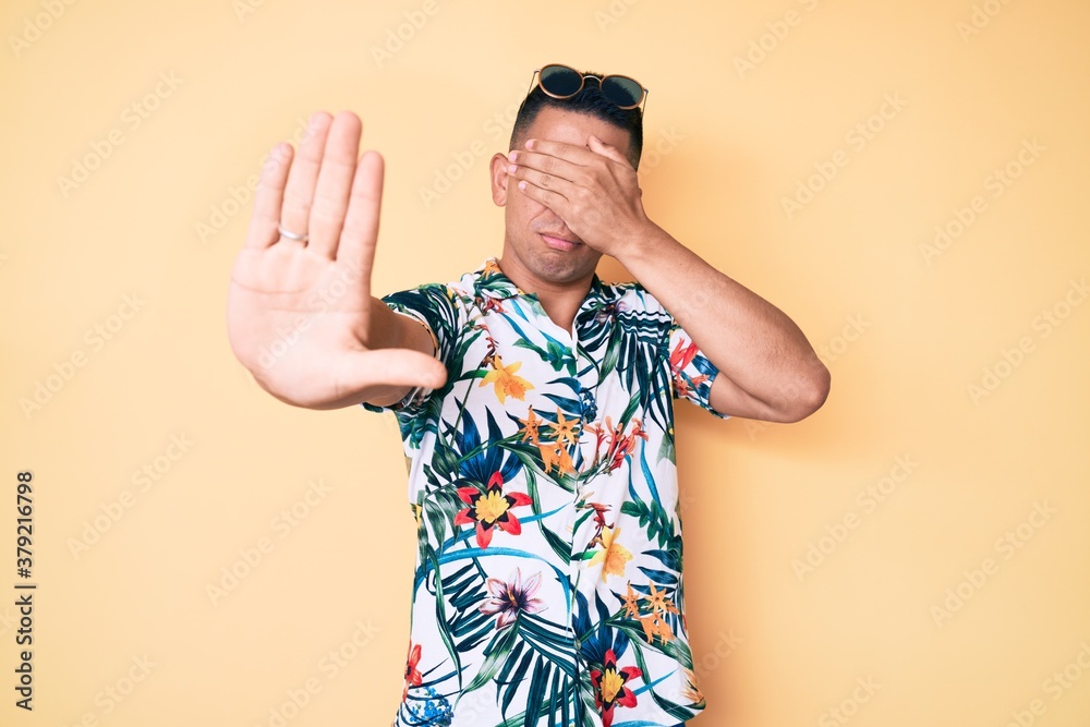 Young handsome latin man wearing summer clothes covering eyes with hands and doing stop gesture with sad and fear expression. embarrassed and negative concept. Young handsome latin man wearing summer clothes covering eyes with hands and doing stop gesture with sad and fear expression. embarrassed and negative concept.