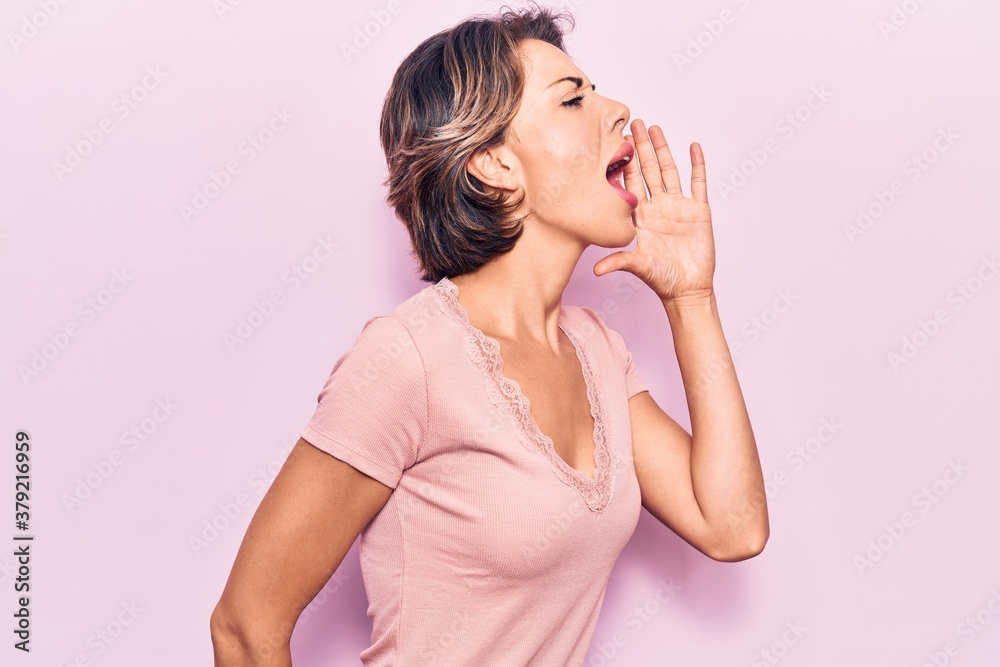 Young beautiful woman wearing casual clothes shouting and screaming loud to side with hand on mouth. communication concept. Young beautiful woman wearing casual clothes shouting and screaming loud to side with hand on mouth. communication concept.