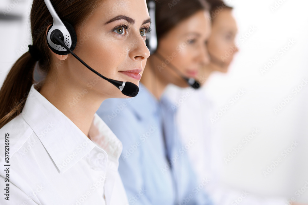 Call center. Group of operators at work. Focus at beautiful business woman in headset Call center. Group of operators at work. Focus at beautiful business woman in headset