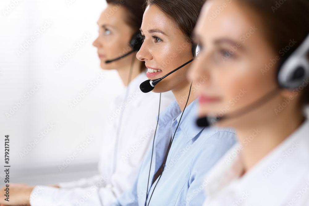 Call center. Group of operators at work. Focus at beautiful business woman in headset Call center. Group of operators at work. Focus at beautiful business woman in headset