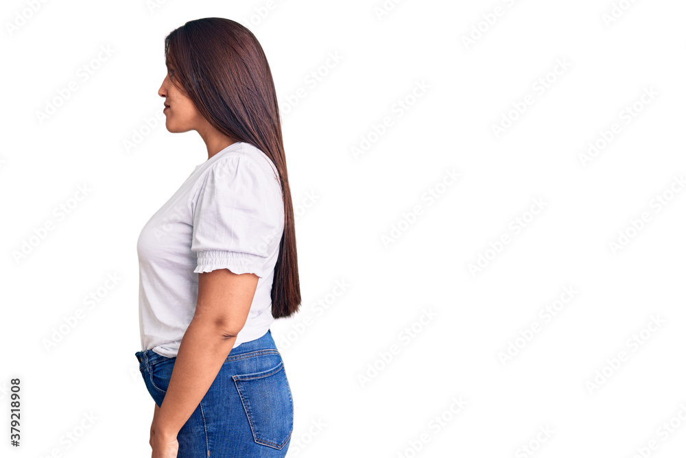Young beautiful brunette woman wearing casual t-shirt looking to side, relax profile pose with natural face with confident smile. Young beautiful brunette woman wearing casual t-shirt looking to side, relax profile pose with natural face with confident smile.