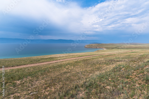 Picturesque sky over the Maloye More Strait. Federal highway on the steppe coast of Olkhon Island.