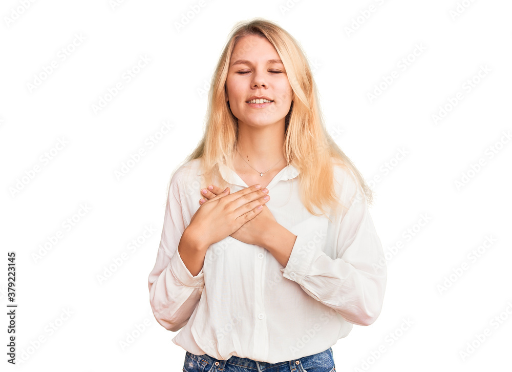 Young beautiful blonde woman wearing casual shirt smiling with hands on chest with closed eyes and grateful gesture on face. health concept. Young beautiful blonde woman wearing casual shirt smiling with hands on chest with closed eyes and grateful gesture on face. health concept.