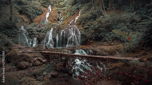 Active lifestyle traveler man standing on background Pucak manik Waterfall is one of the most beautiful waterfalls in Bali located north of Lake Buyan. Indonesia. 4K photo