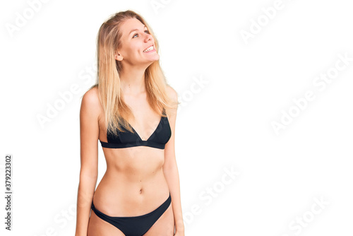 Young beautiful blonde woman wearing bikini looking away to side with smile on face, natural expression. laughing confident.