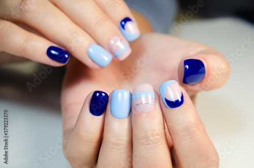 Hands of a young woman with a manicure and blue gel Polish.