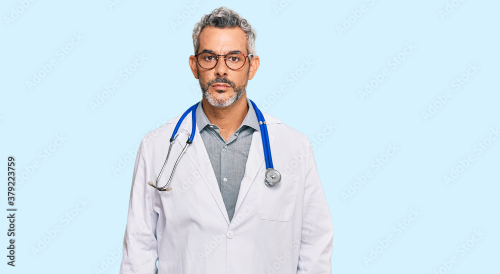 Middle age grey-haired man wearing doctor uniform and stethoscope with serious expression on face. simple and natural looking at the camera. Middle age grey-haired man wearing doctor uniform and stethoscope with serious expression on face. simple and natural looking at the camera.
