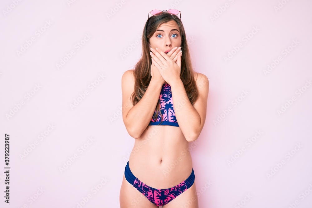 Beautiful young caucasian woman wearing bikini and sunglasses shocked covering mouth with hands for mistake. secret concept. Beautiful young caucasian woman wearing bikini and sunglasses shocked covering mouth with hands for mistake. secret concept.