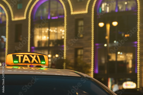 Illuminated orange taxi sign on a white car. Luminous scoreboard. photo