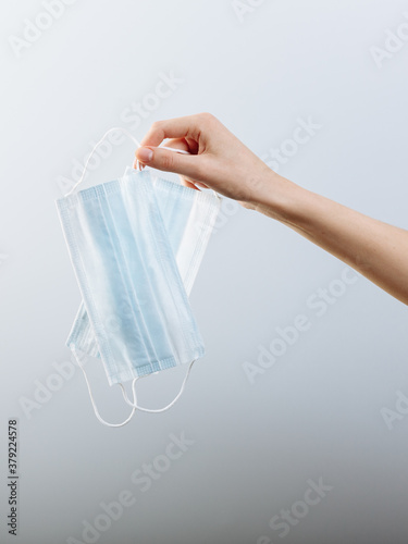 A women's hand holds a medical masks isolated in white background