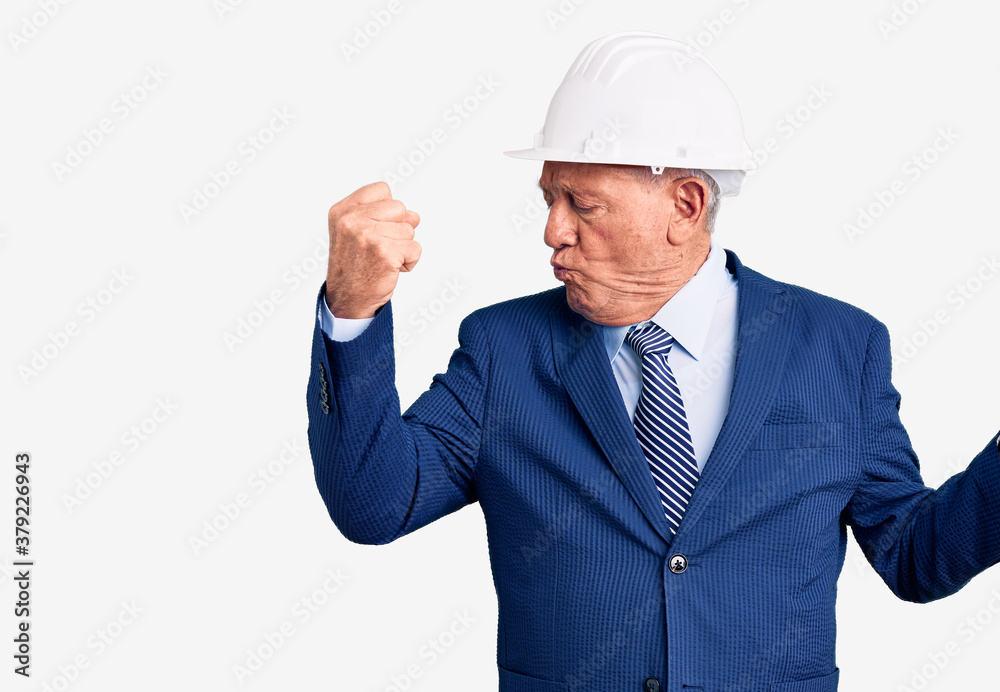Senior handsome grey-haired man wearing suit and architect hardhat showing arms muscles smiling proud. fitness concept. Senior handsome grey-haired man wearing suit and architect hardhat showing arms muscles smiling proud. fitness concept.