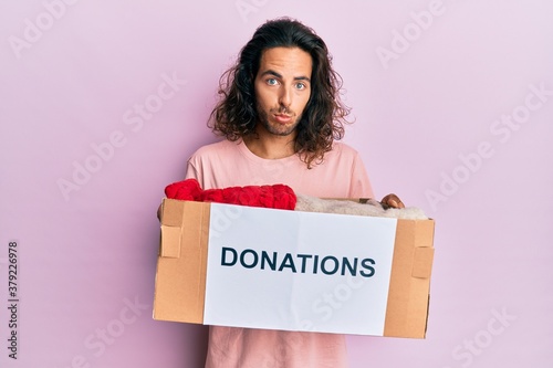 Young handsome man with long hair holding donations box for charity depressed and worry for distress, crying angry and afraid. sad expression. © Krakenimages.com