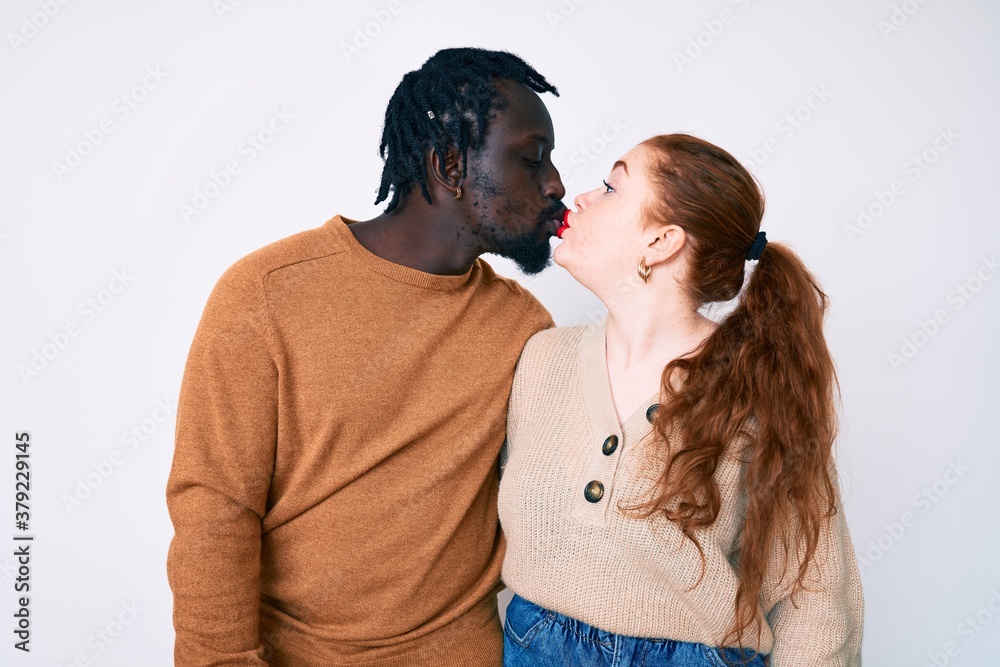 Interracial couple wearing casual clothes looking at the camera blowing a kiss on air being lovely and sexy. love expression. Interracial couple wearing casual clothes looking at the camera blowing a kiss on air being lovely and sexy. love expression.