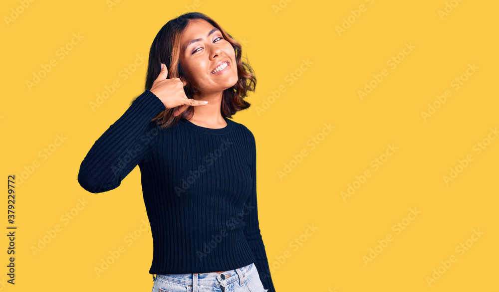 Young beautiful mixed race woman wearing casual clothes smiling doing phone gesture with hand and fingers like talking on the telephone. communicating concepts. Young beautiful mixed race woman wearing casual clothes smiling doing phone gesture with hand and fingers like talking on the telephone. communicating concepts.