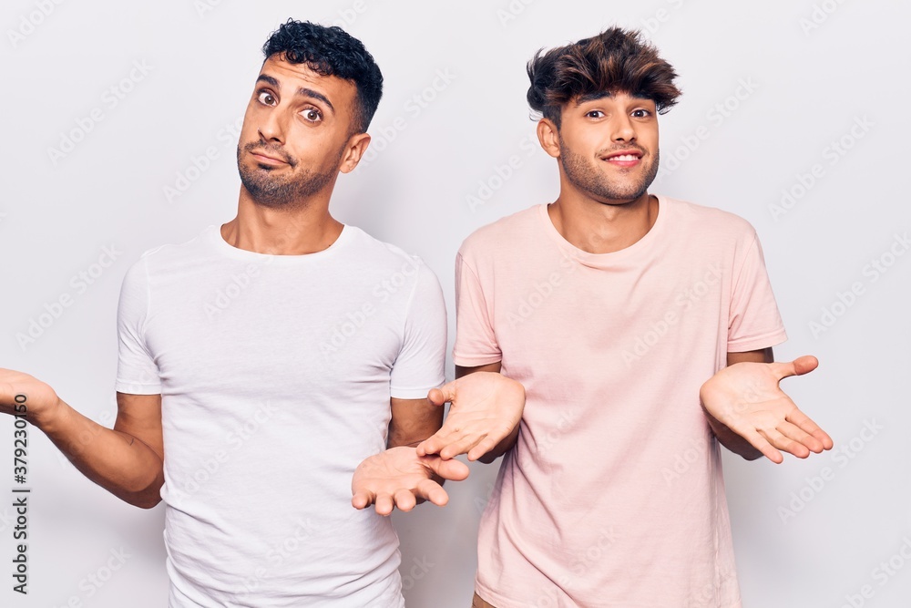 Young gay couple wearing casual clothes clueless and confused expression with arms and hands raised. doubt concept. Young gay couple wearing casual clothes clueless and confused expression with arms and hands raised. doubt concept.