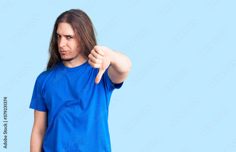 Young adult man with long hair wearing swimwear looking unhappy and angry showing rejection and negative with thumbs down gesture. bad expression. Young adult man with long hair wearing swimwear looking unhappy and angry showing rejection and negative with thumbs down gesture. bad expression.