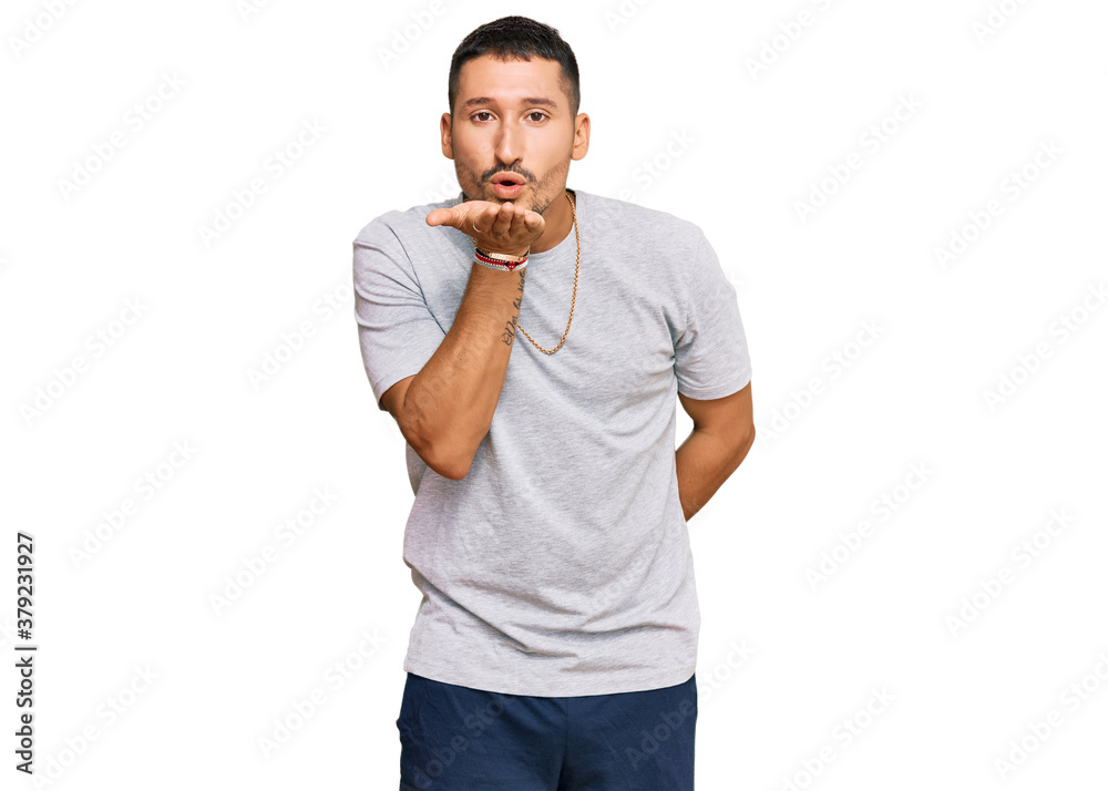 Handsome man with tattoos wearing 90s style looking at the camera blowing a kiss with hand on air being lovely and sexy. love expression. Handsome man with tattoos wearing 90s style looking at the camera blowing a kiss with hand on air being lovely and sexy. love expression.