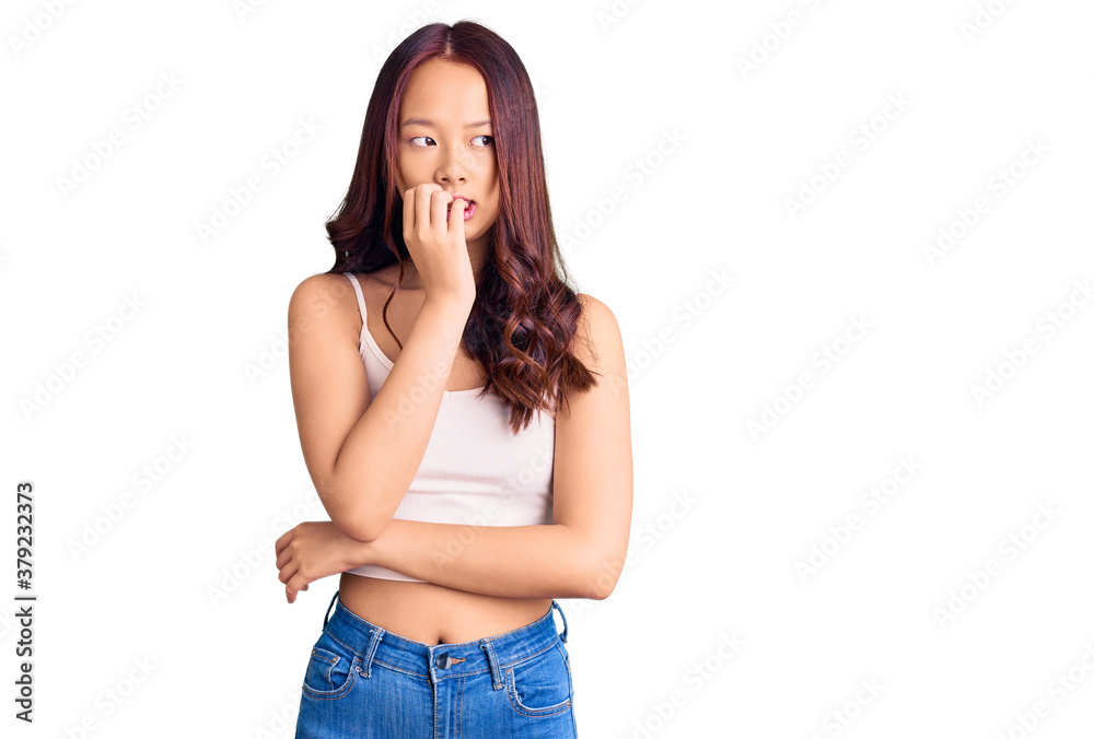 Young beautiful chinese girl wearing casual clothes looking stressed and nervous with hands on mouth biting nails. anxiety problem. Young beautiful chinese girl wearing casual clothes looking stressed and nervous with hands on mouth biting nails. anxiety problem.
