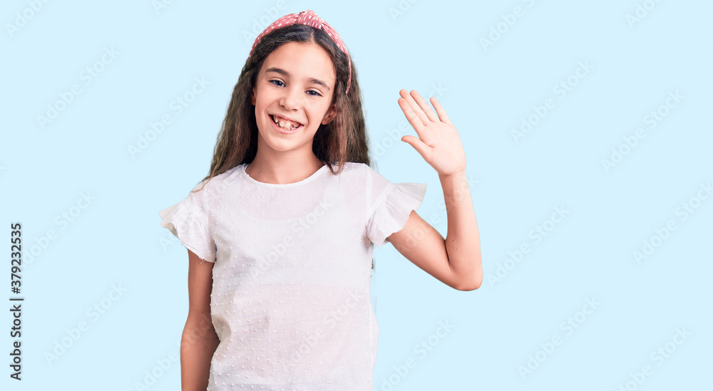 Cute hispanic child girl wearing casual white tshirt waiving saying hello happy and smiling, friendly welcome gesture Cute hispanic child girl wearing casual white tshirt waiving saying hello happy and smiling, friendly welcome gesture