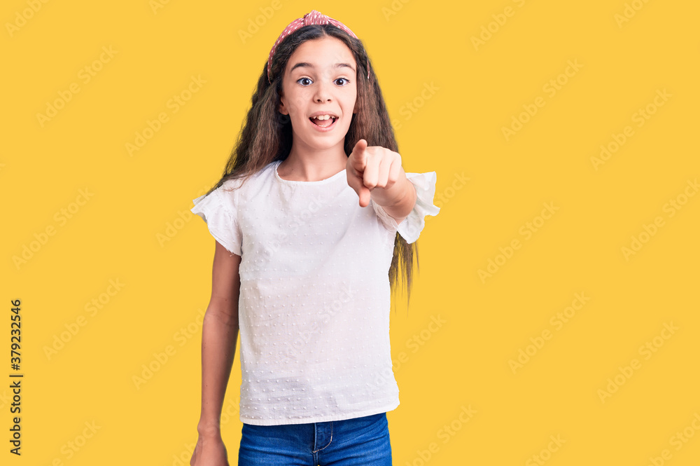 Cute hispanic child girl wearing casual white tshirt pointing displeased and frustrated to the camera, angry and furious with you Cute hispanic child girl wearing casual white tshirt pointing displeased and frustrated to the camera, angry and furious with you