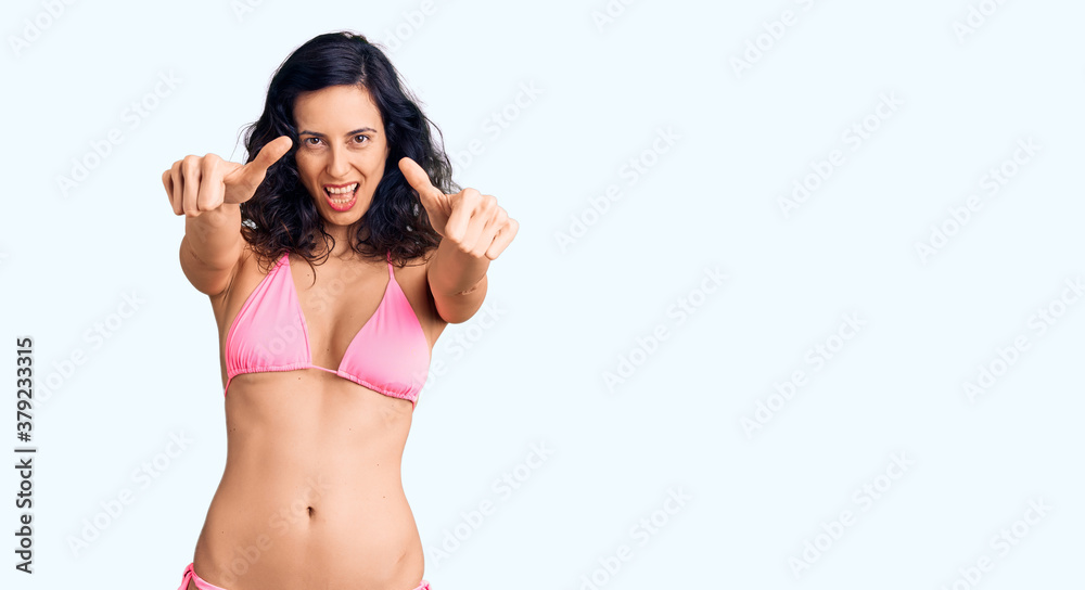 Young beautiful hispanic woman wearing bikini approving doing positive gesture with hand, thumbs up smiling and happy for success. winner gesture. Young beautiful hispanic woman wearing bikini approving doing positive gesture with hand, thumbs up smiling and happy for success. winner gesture.