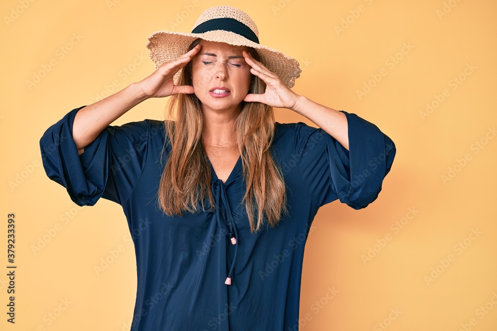 Middle age hispanic woman wearing summer hat suffering from headache desperate and stressed because pain and migraine. hands on head. Middle age hispanic woman wearing summer hat suffering from headache desperate and stressed because pain and migraine. hands on head.