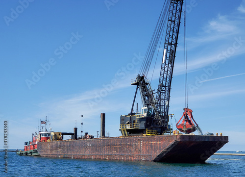 Canvas derrick barge in Lake Michigan harbor dredging the channel.