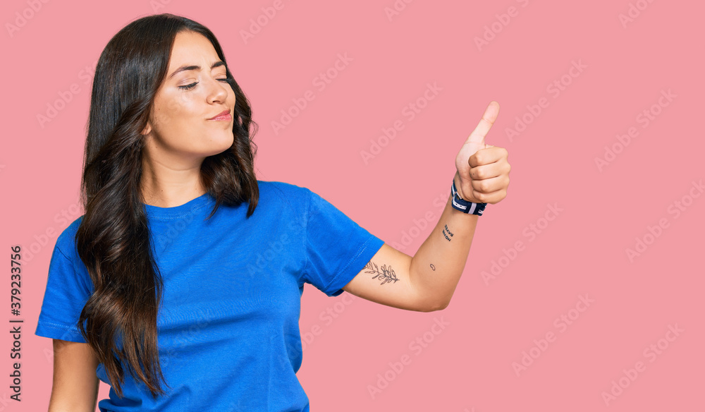 Beautiful brunette young woman wearing casual clothes looking proud, smiling doing thumbs up gesture to the side Beautiful brunette young woman wearing casual clothes looking proud, smiling doing thumbs up gesture to the side