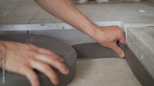 Floor repair. Worker glues special protection so as not to damage the baseboard