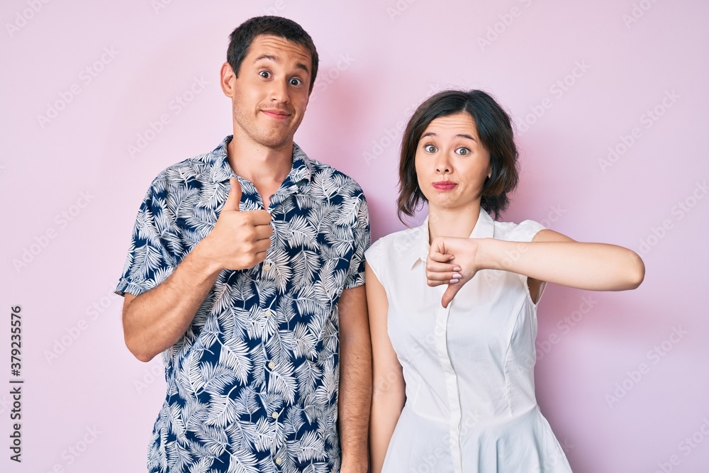 Beautiful couple wearing casual clothes doing thumbs up and down, disagreement and agreement expression. crazy conflict Beautiful couple wearing casual clothes doing thumbs up and down, disagreement and agreement expression. crazy conflict