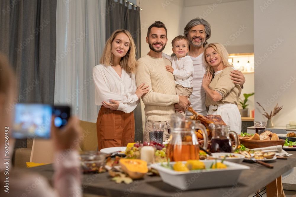 Cheerful and affectionate three generation family standing by festive table Cheerful and affectionate three generation family standing by festive table