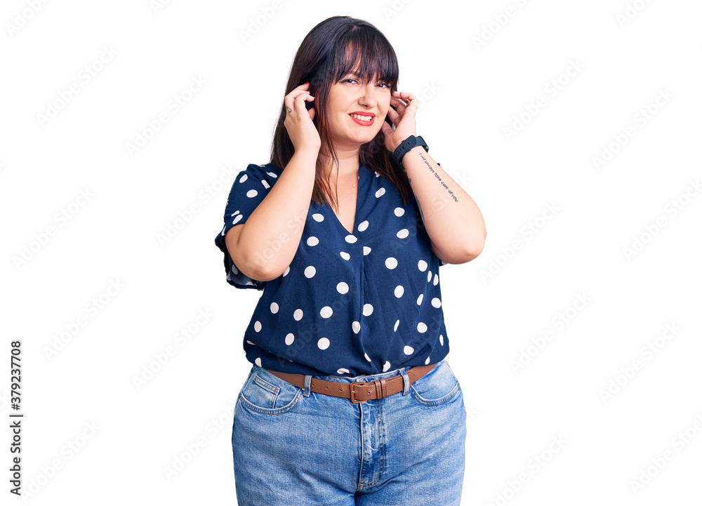 Young plus size woman wearing casual clothes covering ears with fingers with annoyed expression for the noise of loud music. deaf concept. Young plus size woman wearing casual clothes covering ears with fingers with annoyed expression for the noise of loud music. deaf concept.