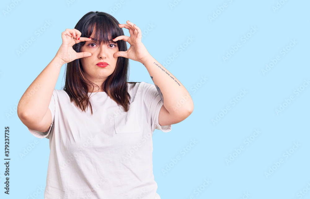 Young plus size woman wearing casual clothes trying to open eyes with fingers, sleepy and tired for morning fatigue Young plus size woman wearing casual clothes trying to open eyes with fingers, sleepy and tired for morning fatigue
