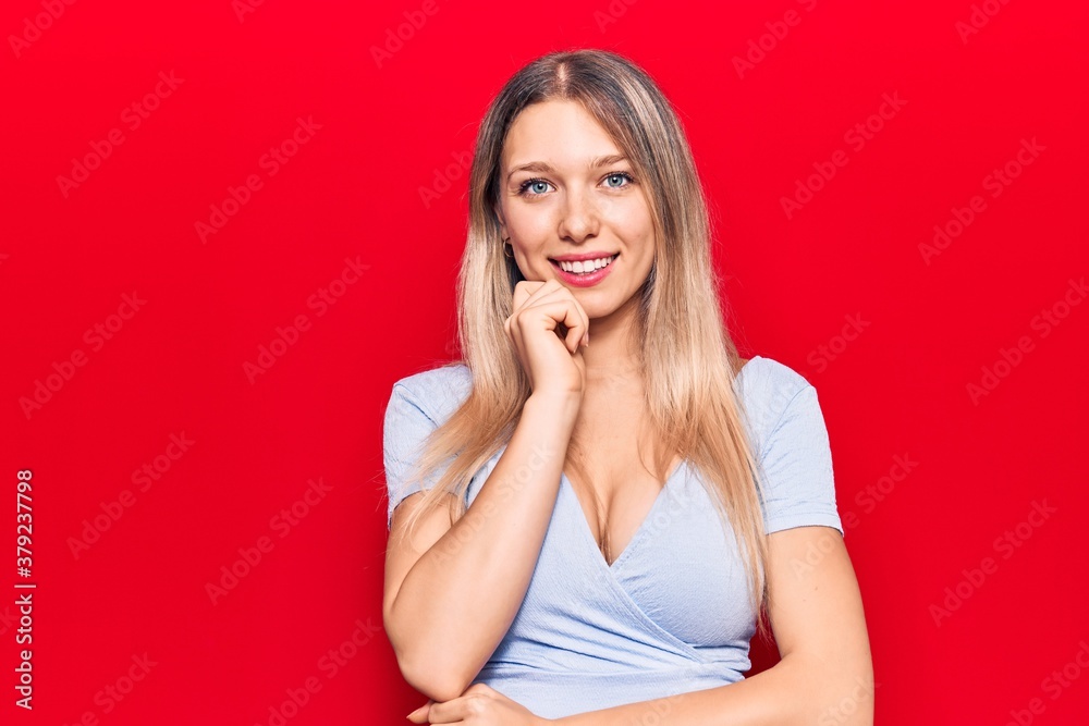 Young blonde woman wearing casual clothes smiling looking confident at the camera with crossed arms and hand on chin. thinking positive. Young blonde woman wearing casual clothes smiling looking confident at the camera with crossed arms and hand on chin. thinking positive.