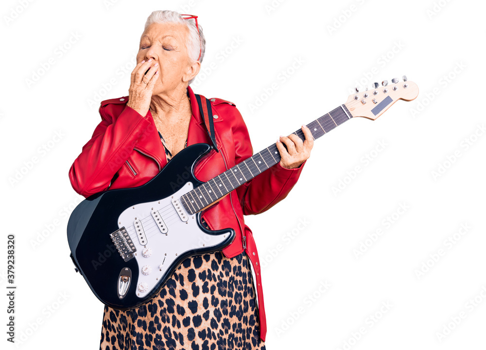 Senior beautiful woman with blue eyes and grey hair wearing a modern look playing electric guitar bored yawning tired covering mouth with hand. restless and sleepiness.