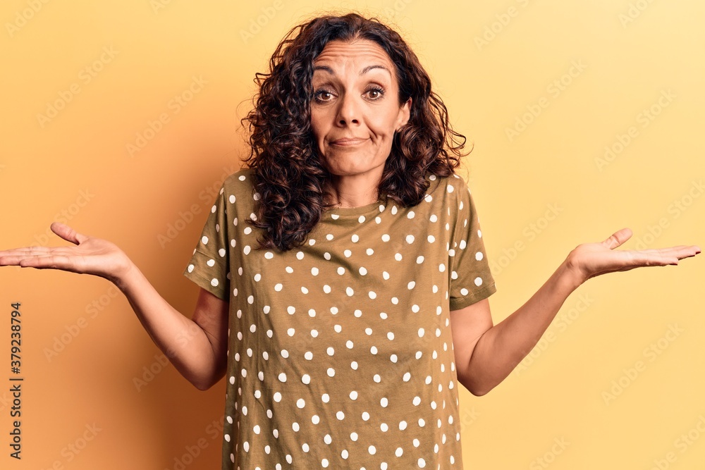 Middle age beautiful woman wearing casual t shirt clueless and confused with open arms, no idea and doubtful face. Middle age beautiful woman wearing casual t shirt clueless and confused with open arms, no idea and doubtful face.