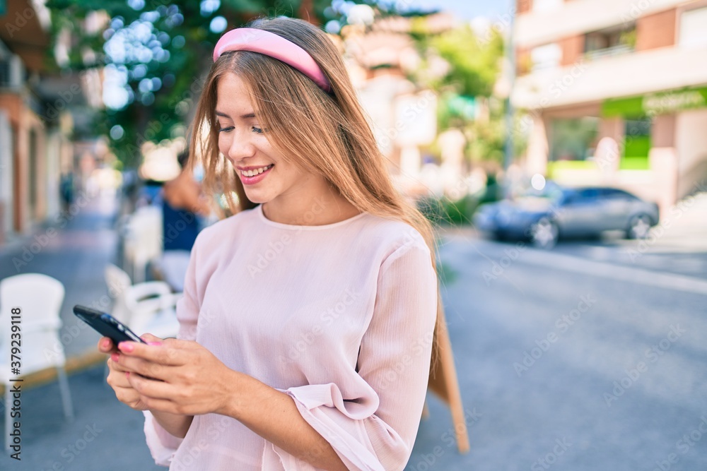 Young caucasian girl smiling happy using smartphone at the city.
