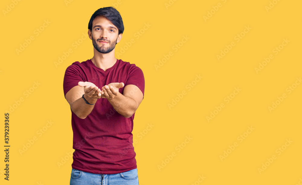 Handsome hispanic man wearing casual clothes smiling with hands palms together receiving or giving gesture. hold and protection Handsome hispanic man wearing casual clothes smiling with hands palms together receiving or giving gesture. hold and protection