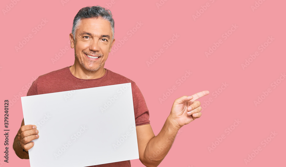 Handsome middle age man holding blank empty banner smiling happy pointing with hand and finger to the side Handsome middle age man holding blank empty banner smiling happy pointing with hand and finger to the side