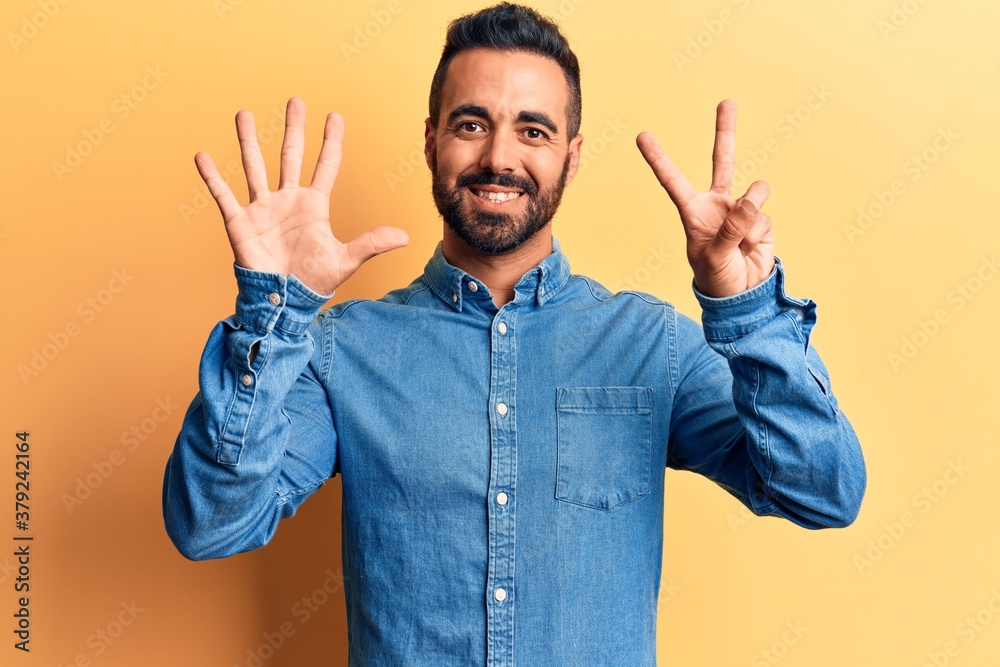 Naklejka premium Young hispanic man wearing casual clothes showing and pointing up with fingers number seven while smiling confident and happy.