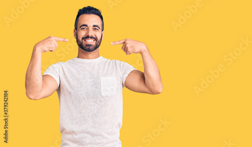 Young hispanic man wearing casual clothes smiling cheerful showing and pointing with fingers teeth and mouth. dental health concept.